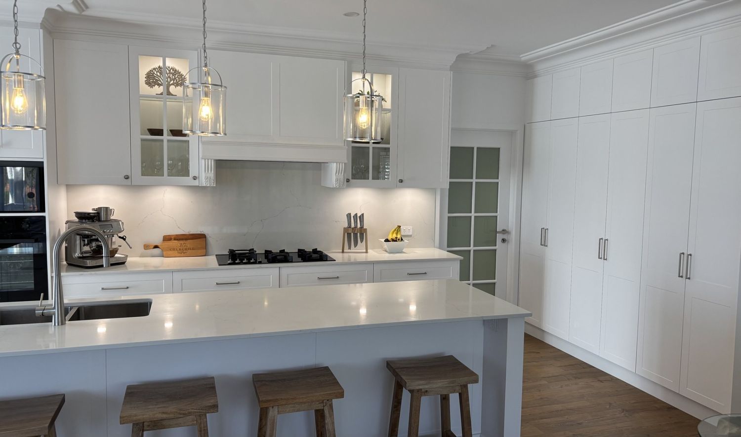 A Kitchen With White Cabinets and Stools and a Large Island — The Kitchen Centre In Tuggerah, NSW