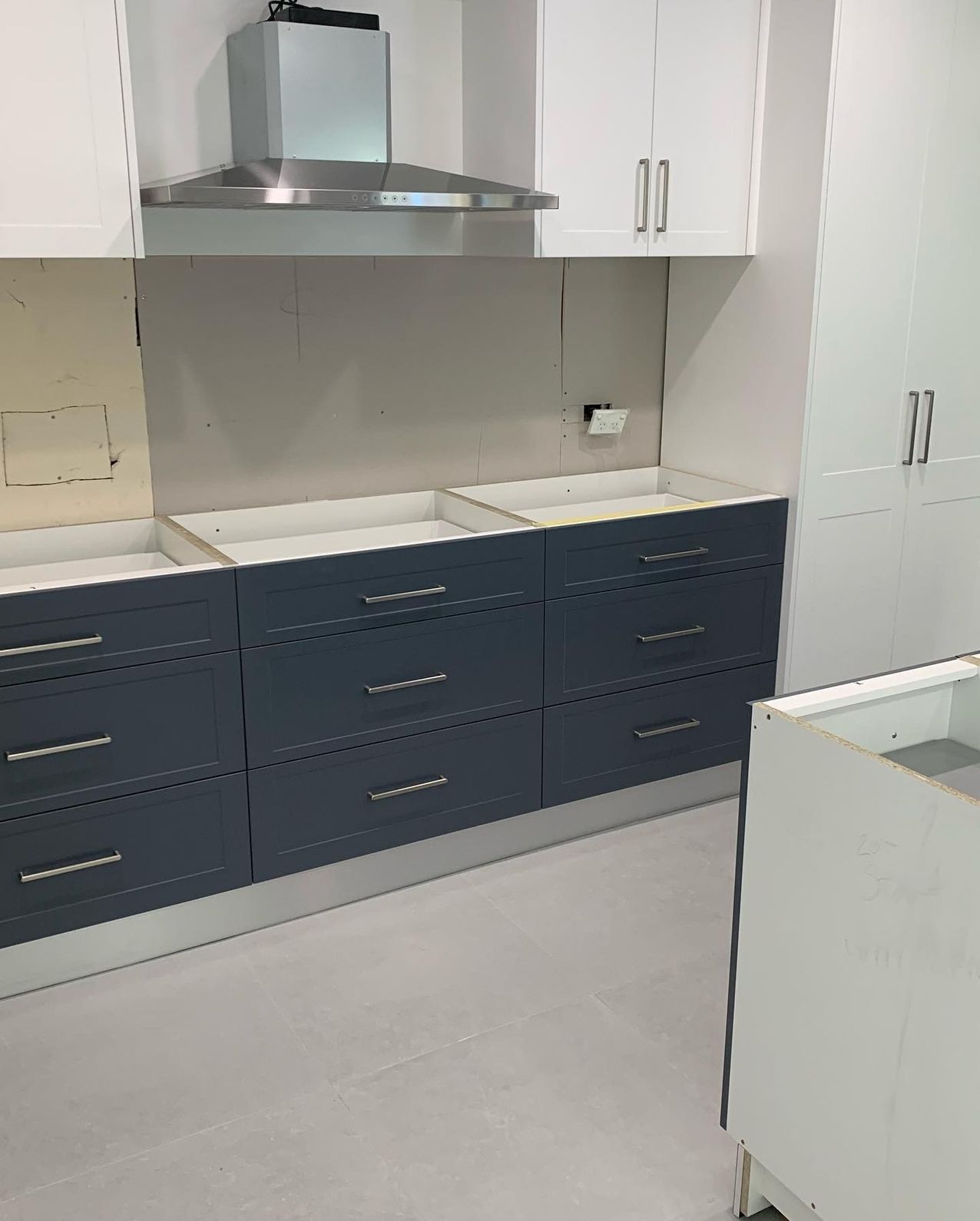 A Kitchen With Blue Cabinets, White Cabinets, and a Stainless Steel Hood — The Kitchen Centre In Wyong, NSW