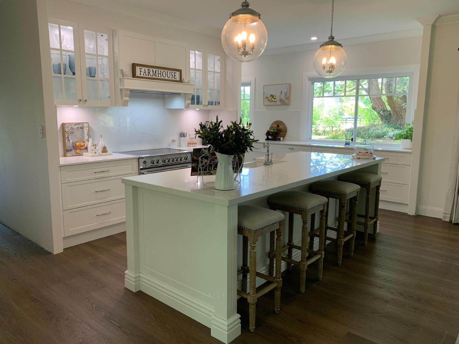 A Kitchen With White Cabinets, Stools, a Large Island and a Stove — The Kitchen Centre In Erina, NSW