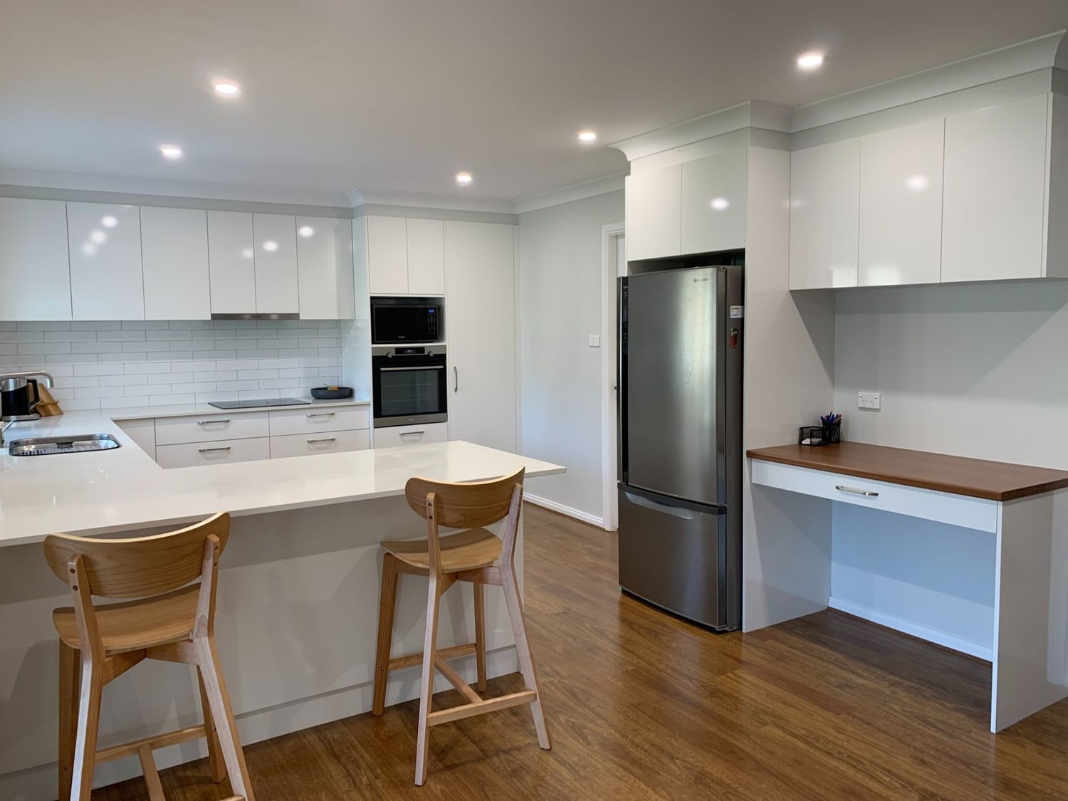 A Kitchen With White Cabinets, Stools, a Refrigerator, and a Desk — The Kitchen Centre In Erina, NSW