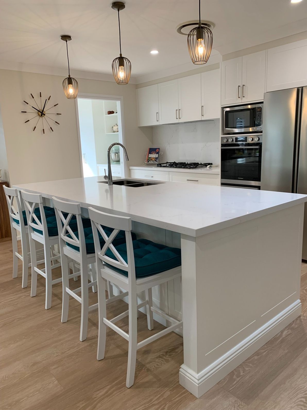 A Kitchen With a Large Island and Stools and a Clock on the Wall — The Kitchen Centre In Gosford, NSW