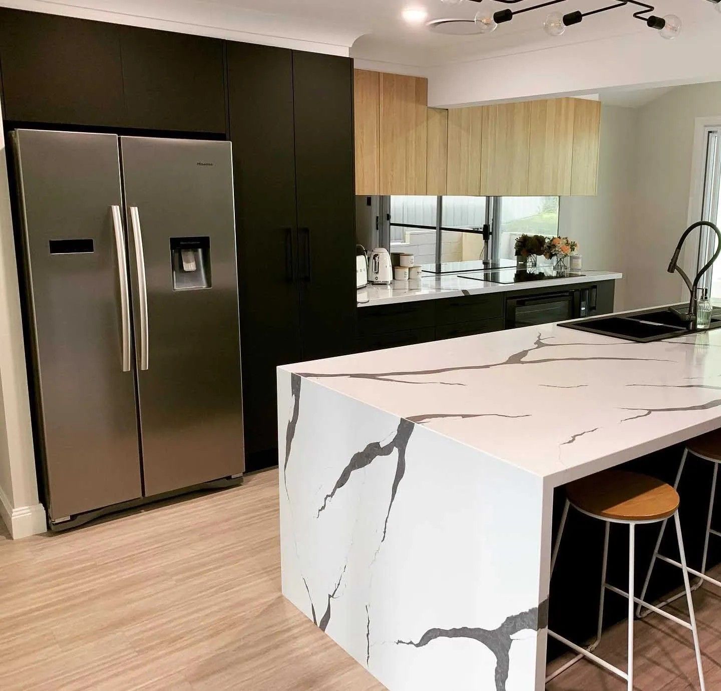 A Kitchen With a Refrigerator and a Large Island With Marble Counter Tops — The Kitchen Centre In Tuggerah, NSW