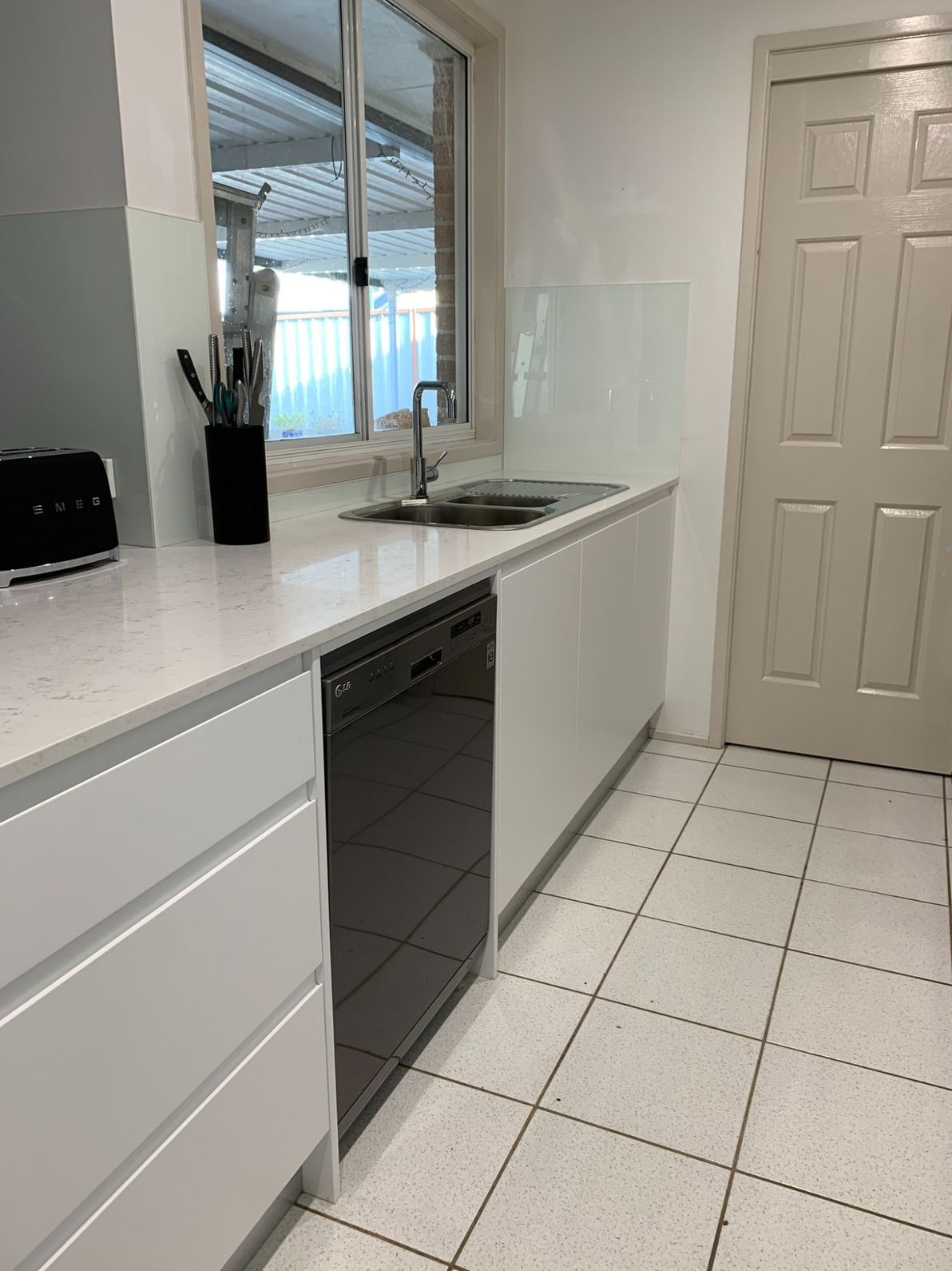 A Kitchen With White Cabinets, a Black Dishwasher, a Sink and a Window — The Kitchen Centre In The Entrance, NSW