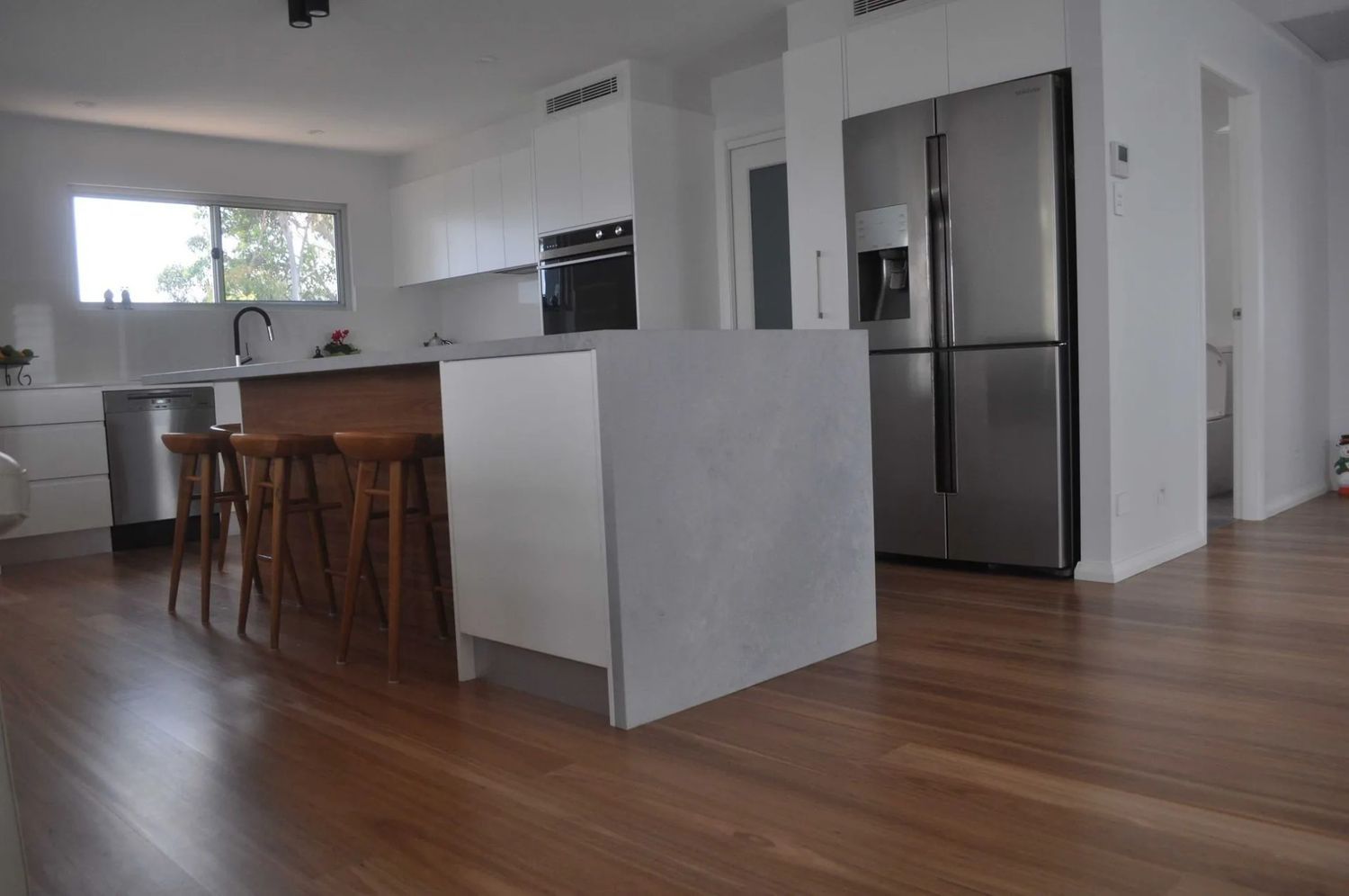 A Kitchen With a Stainless Steel Refrigerator and a Wooden Floor — The Kitchen Centre In Tuggerah, NSW