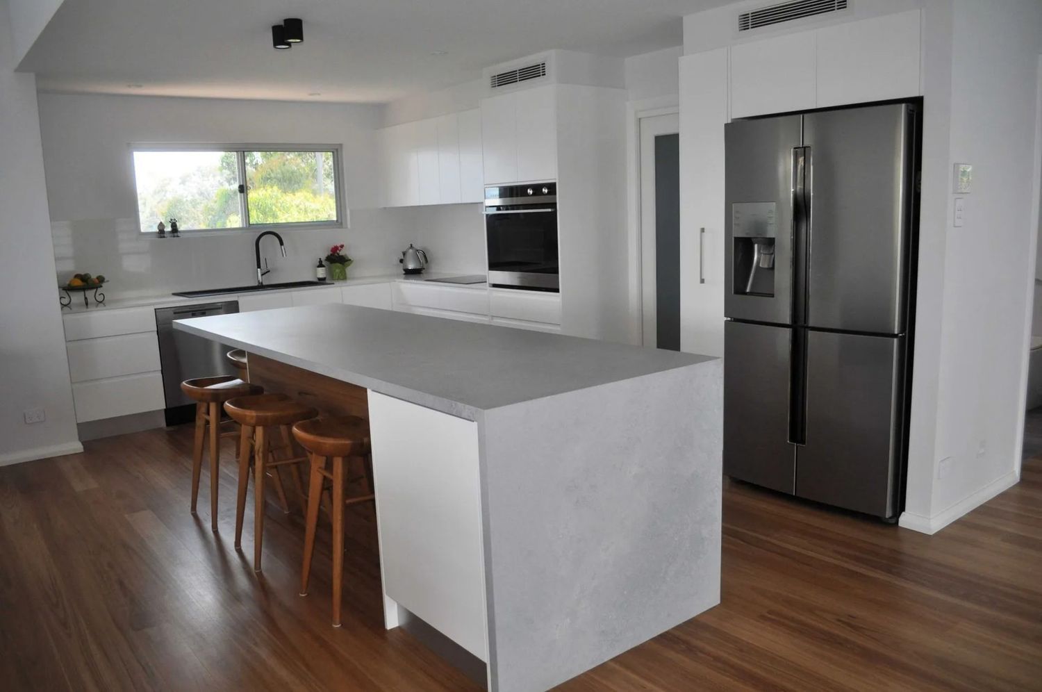 A Kitchen With a Large Island and a Stainless Steel Refrigerator — The Kitchen Centre In Tuggerah, NSW