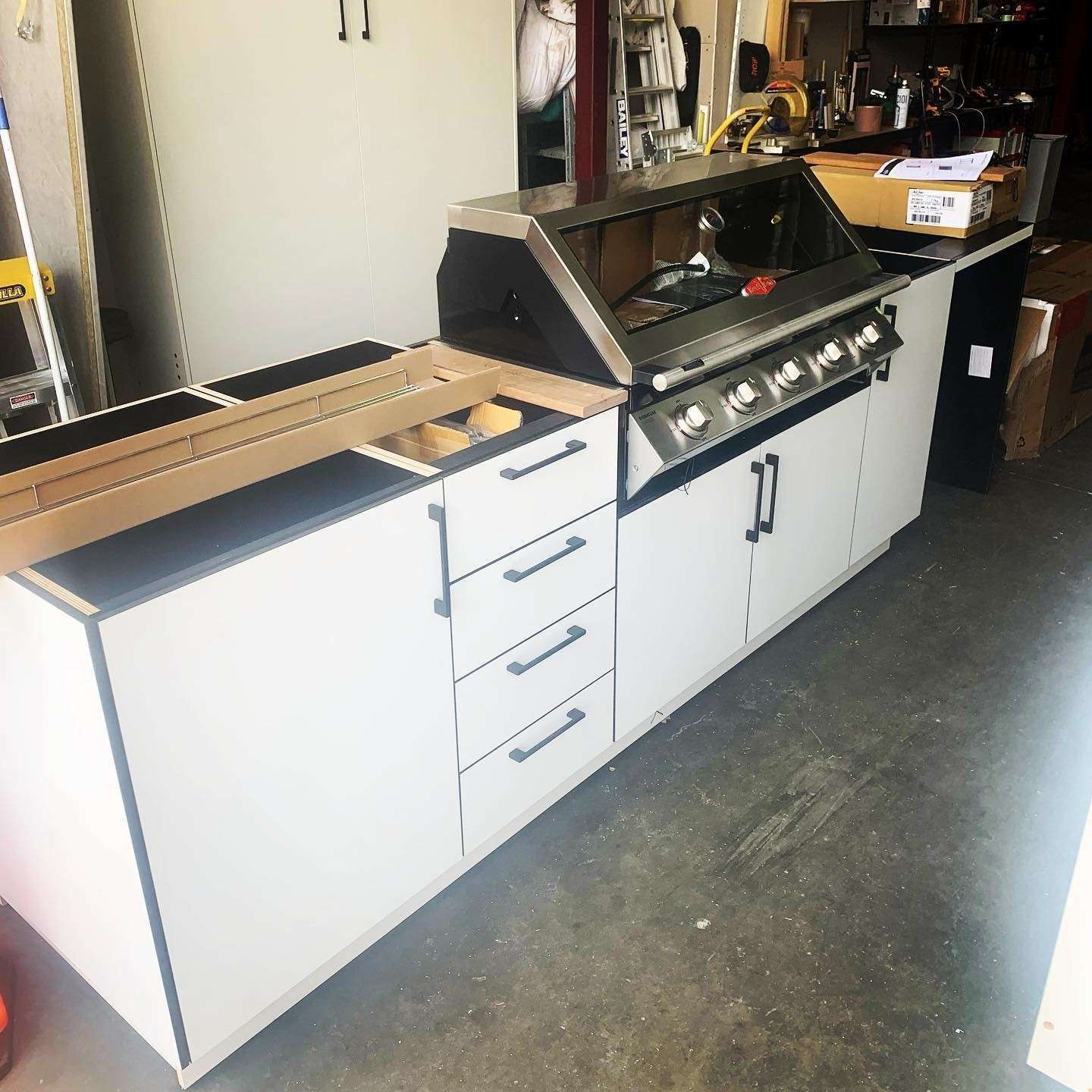 A Kitchen With White Cabinets and Drawers and a Grill — The Kitchen Centre In Tuggerah, NSW