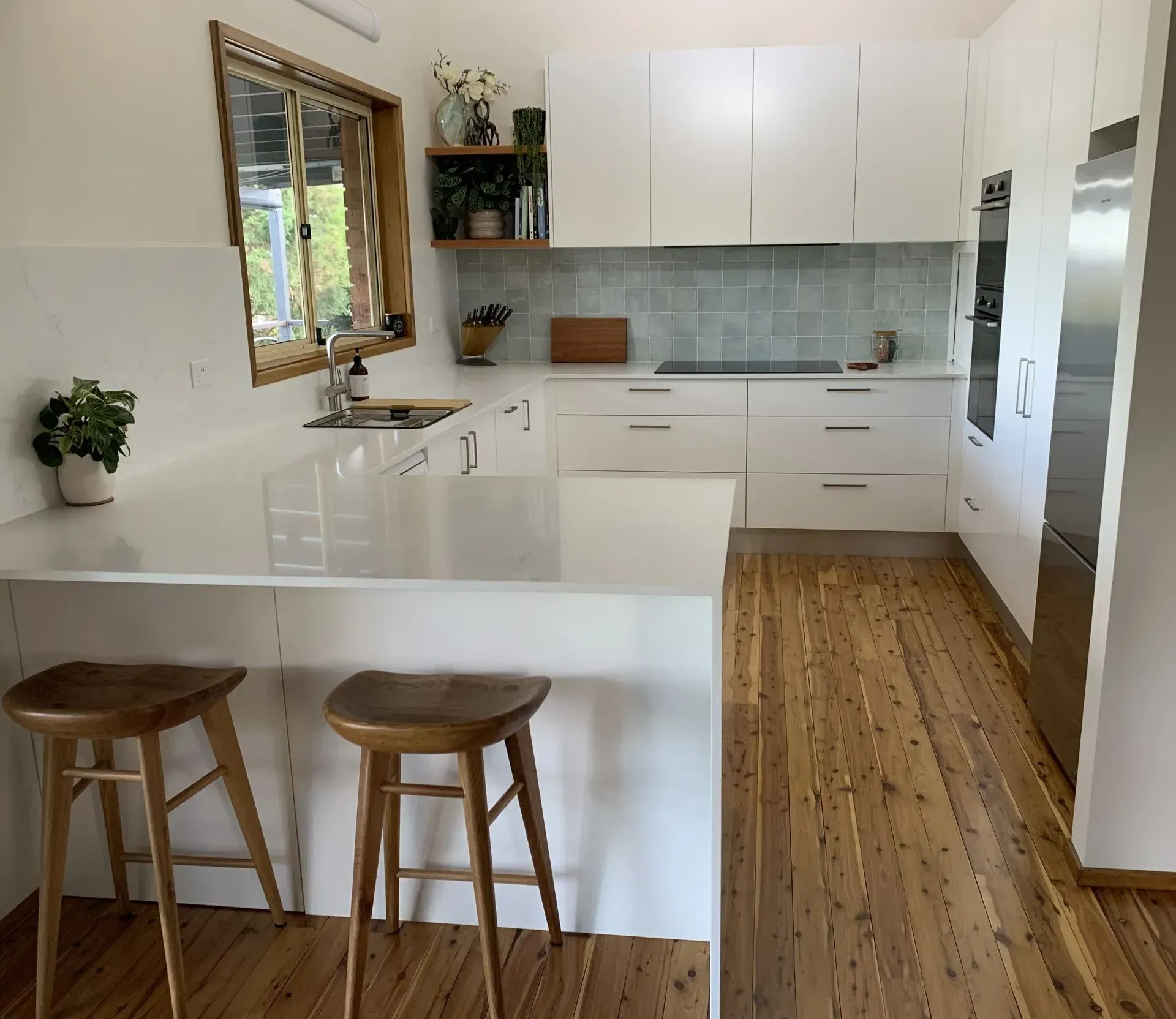 Modern White Kitchen With Wood Floor, White Countertops, and Wooden Bar Stools — The Kitchen Centre In Tuggerah, NSW