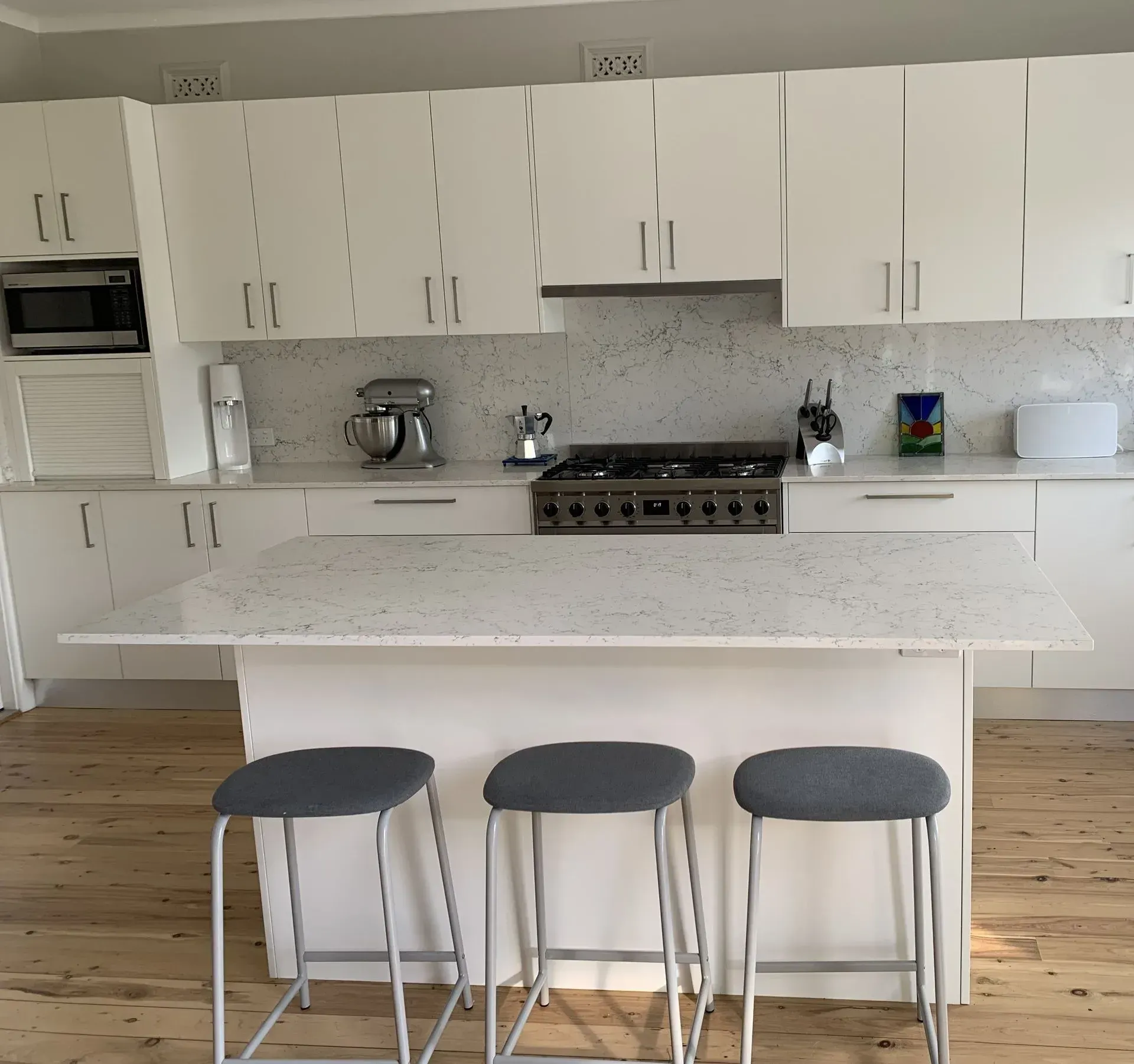 White Kitchen With Island, Stools, Stainless Steel Appliances, and White Countertops — The Kitchen Centre In Tuggerah, NSW