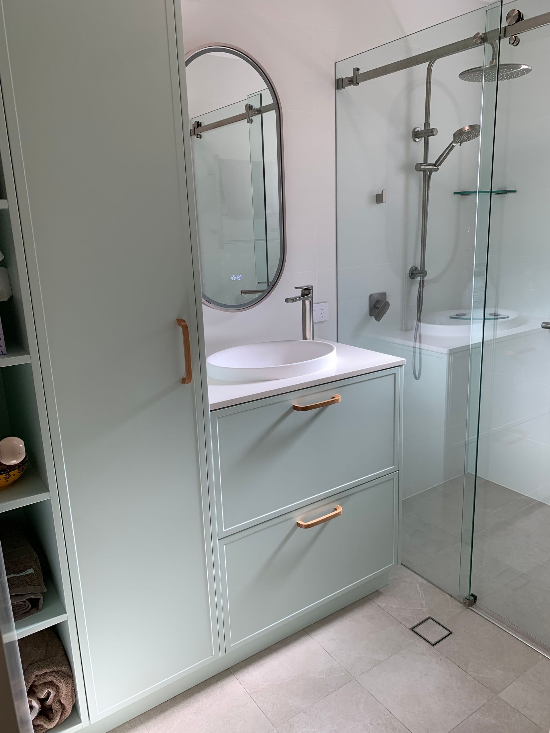 A Bathroom With Green Cabinets, An Oval Mirror, and Gold Handles — The Kitchen Centre In Tuggerah, NSW