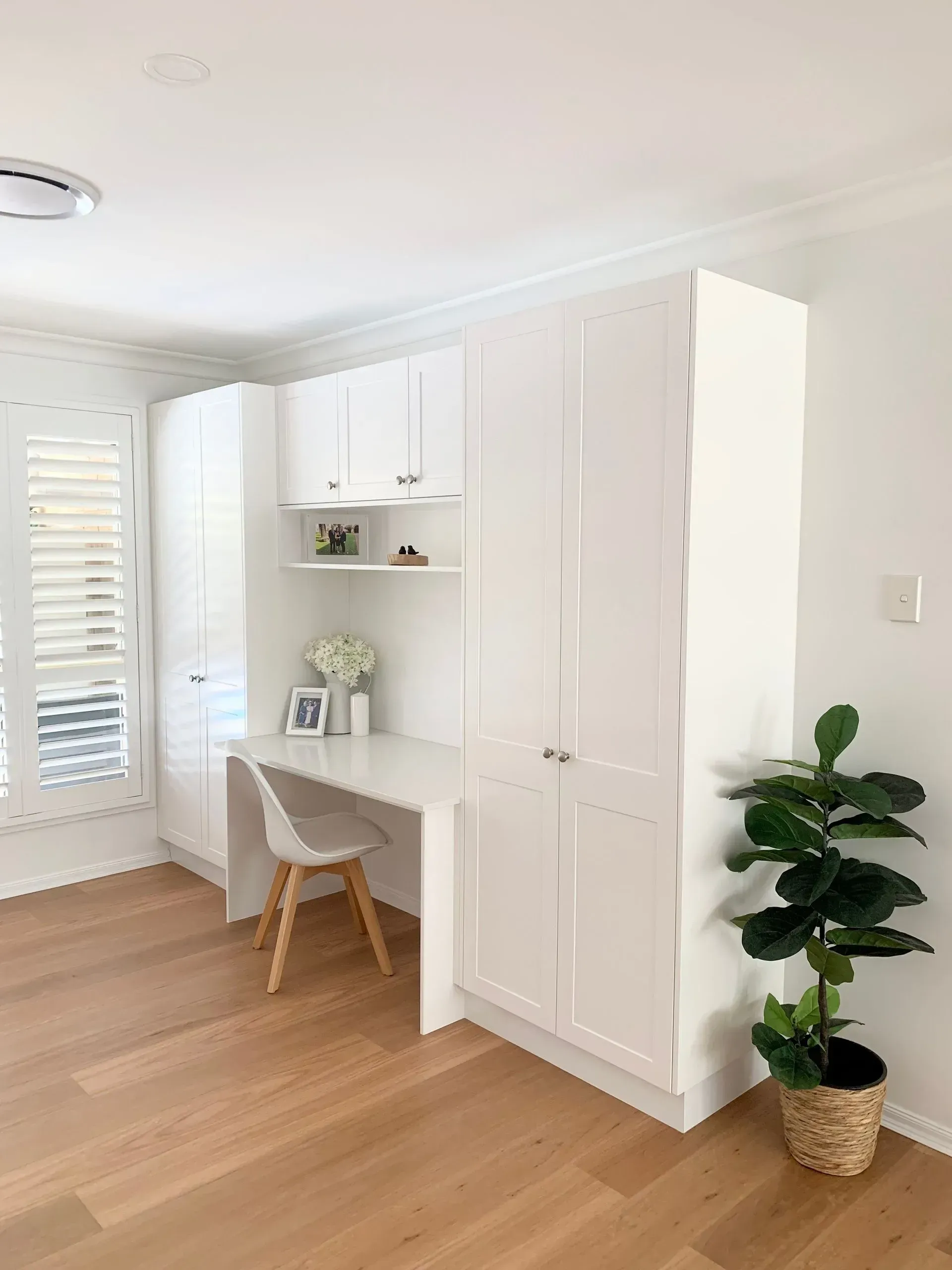 Built-in White Desk and Storage Cabinets in a Room With Wood Floors and a Houseplant — The Kitchen Centre In Tuggerah, NSW