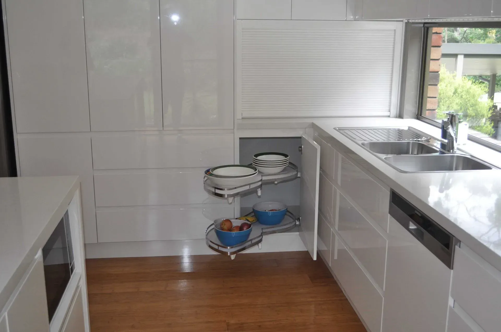 White Kitchen With Pull-out Corner Cabinet Holding Bowls and Countertop Next to a Sink — The Kitchen Centre In Tuggerah, NSW