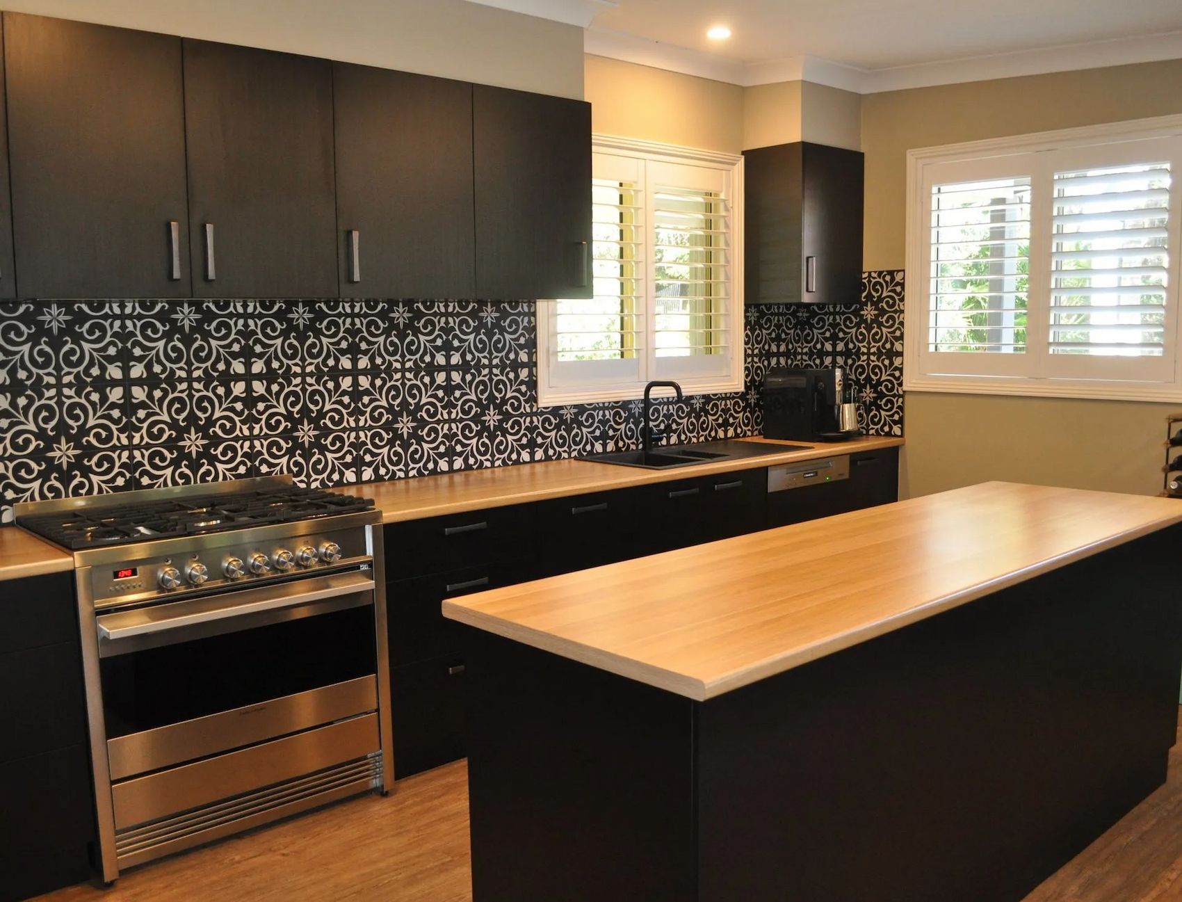 Modern Kitchen With Black Cabinets, Patterned Backsplash, and Light Wood Countertops — The Kitchen Centre In Tuggerah, NSW