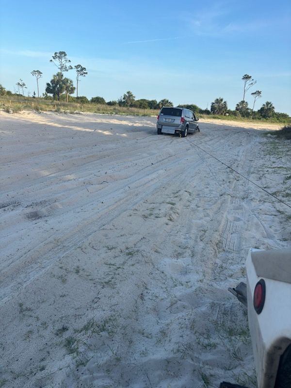 A tow truck is towing a car on the back of it.