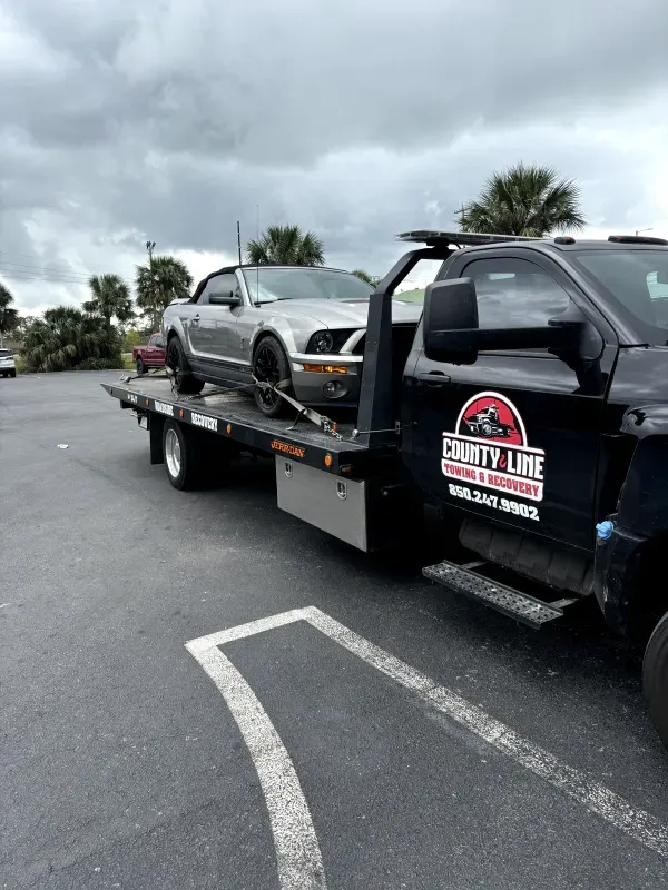 A car is being towed by a tow truck in a parking lot.