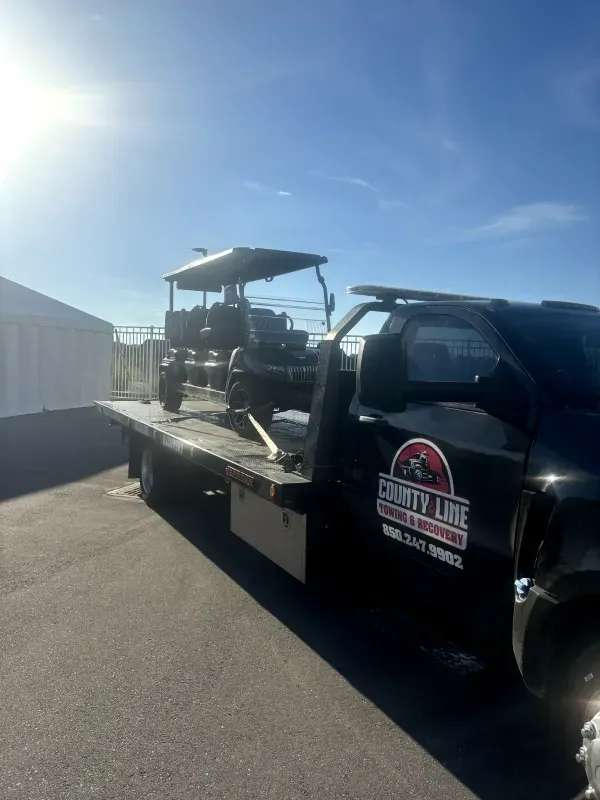 A tow truck with a golf cart on the back of it