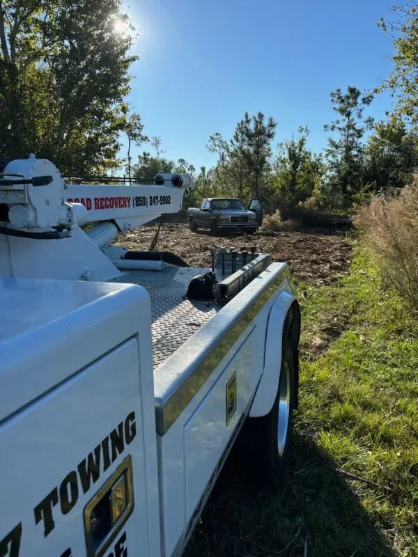 A white towing truck is parked in a grassy field