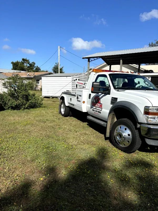 A white tow truck is parked in a grassy field.
