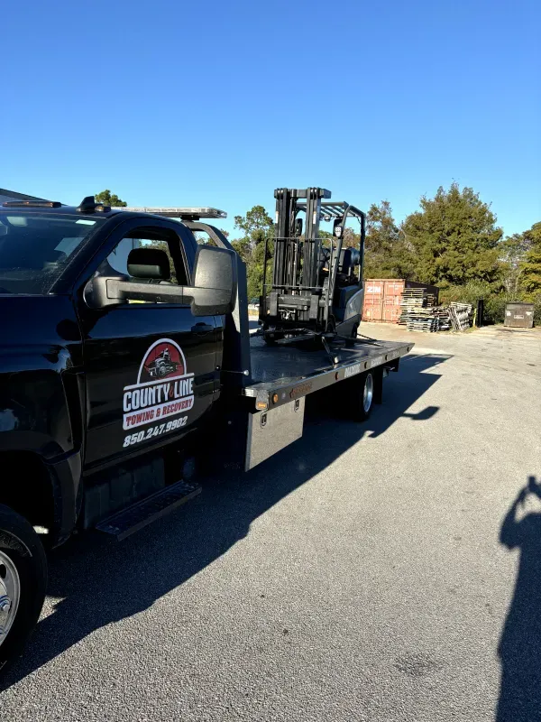 A tow truck with a forklift on the back of it