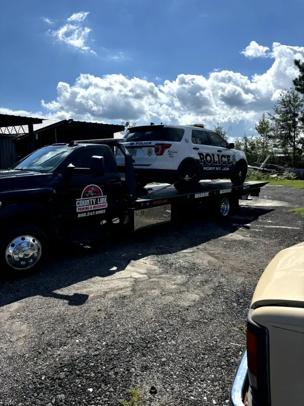 A police car is being towed by a tow truck.