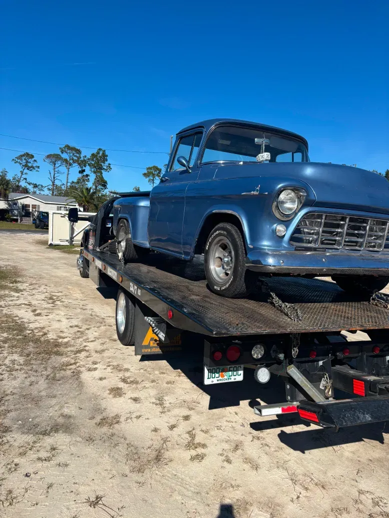 A blue truck is sitting on top of a tow truck.