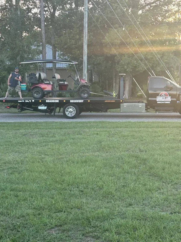 A golf cart is being towed by a tow truck.