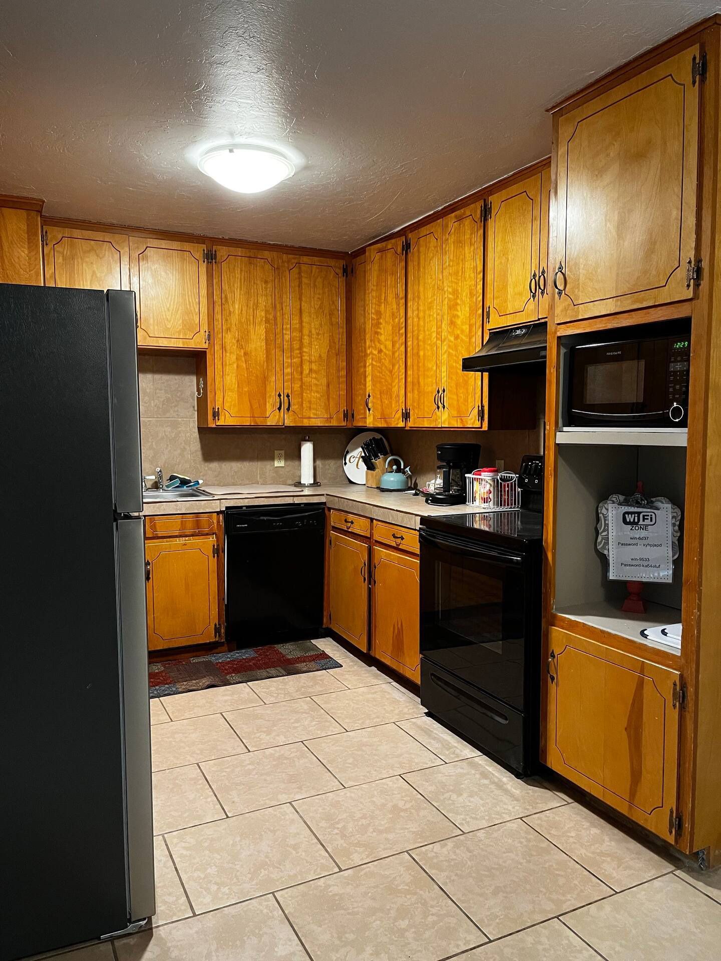 A kitchen with wooden cabinets and a black refrigerator
