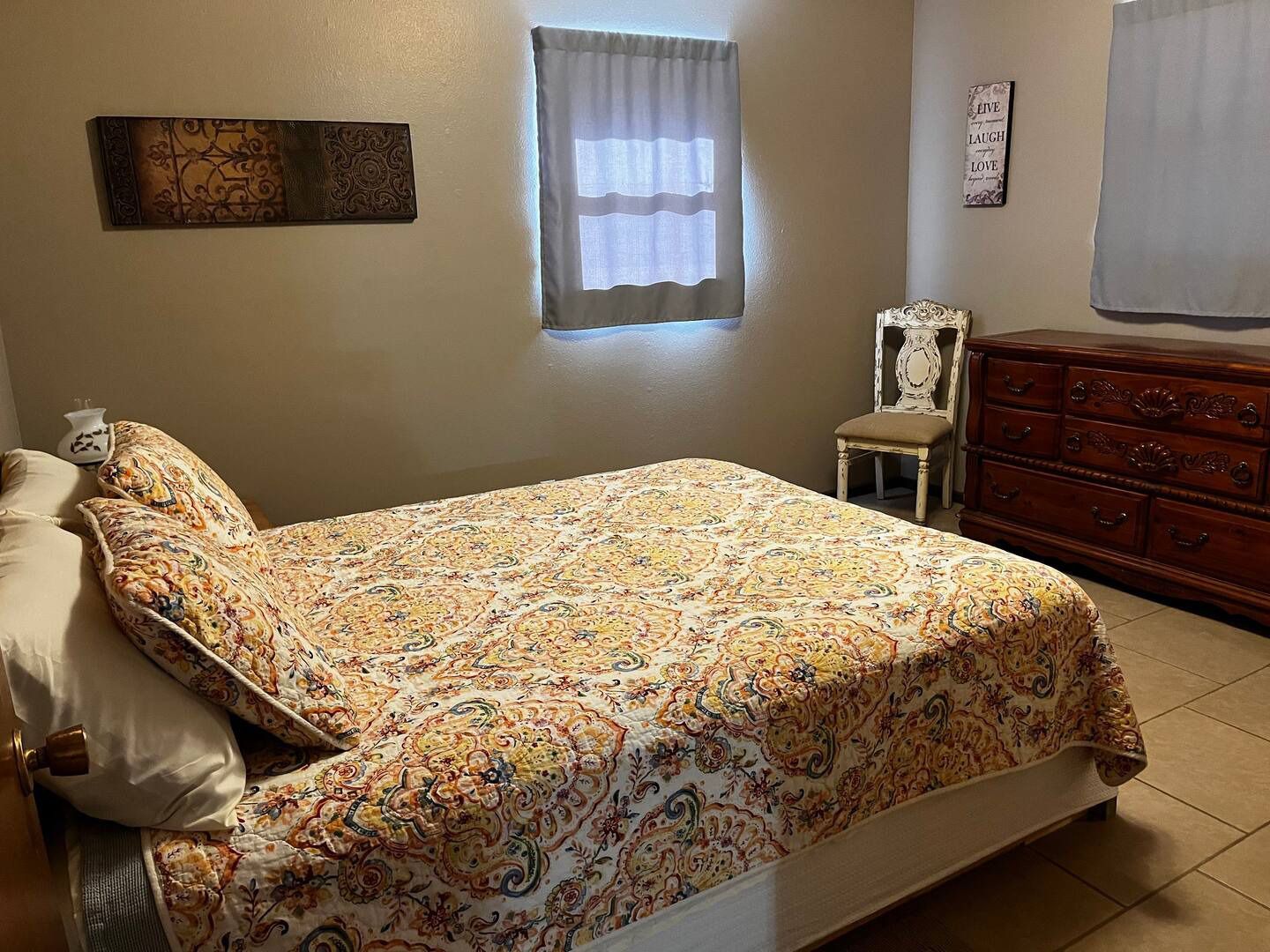 A bedroom with a bed , dresser , chair and window.