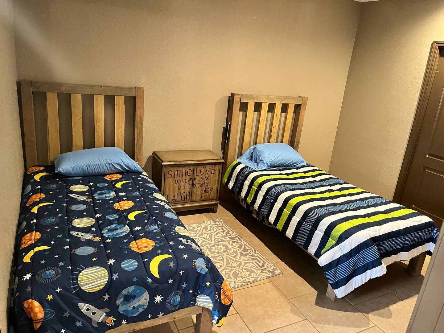 A bedroom with two twin beds and a nightstand.