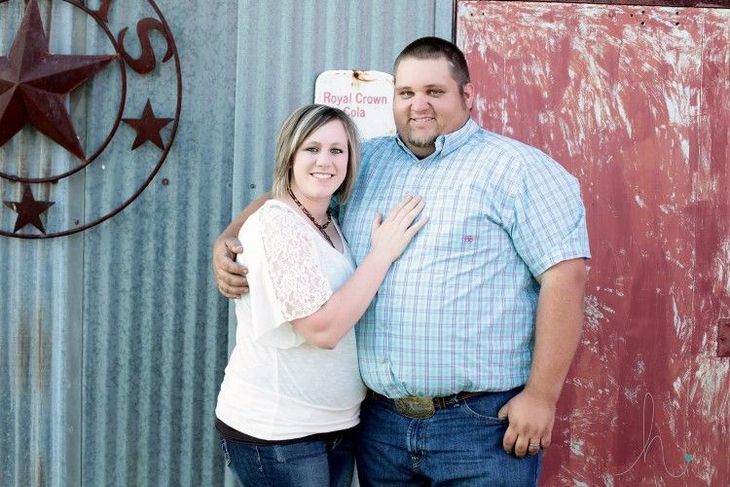 A man and a woman are posing for a picture in front of a red door.