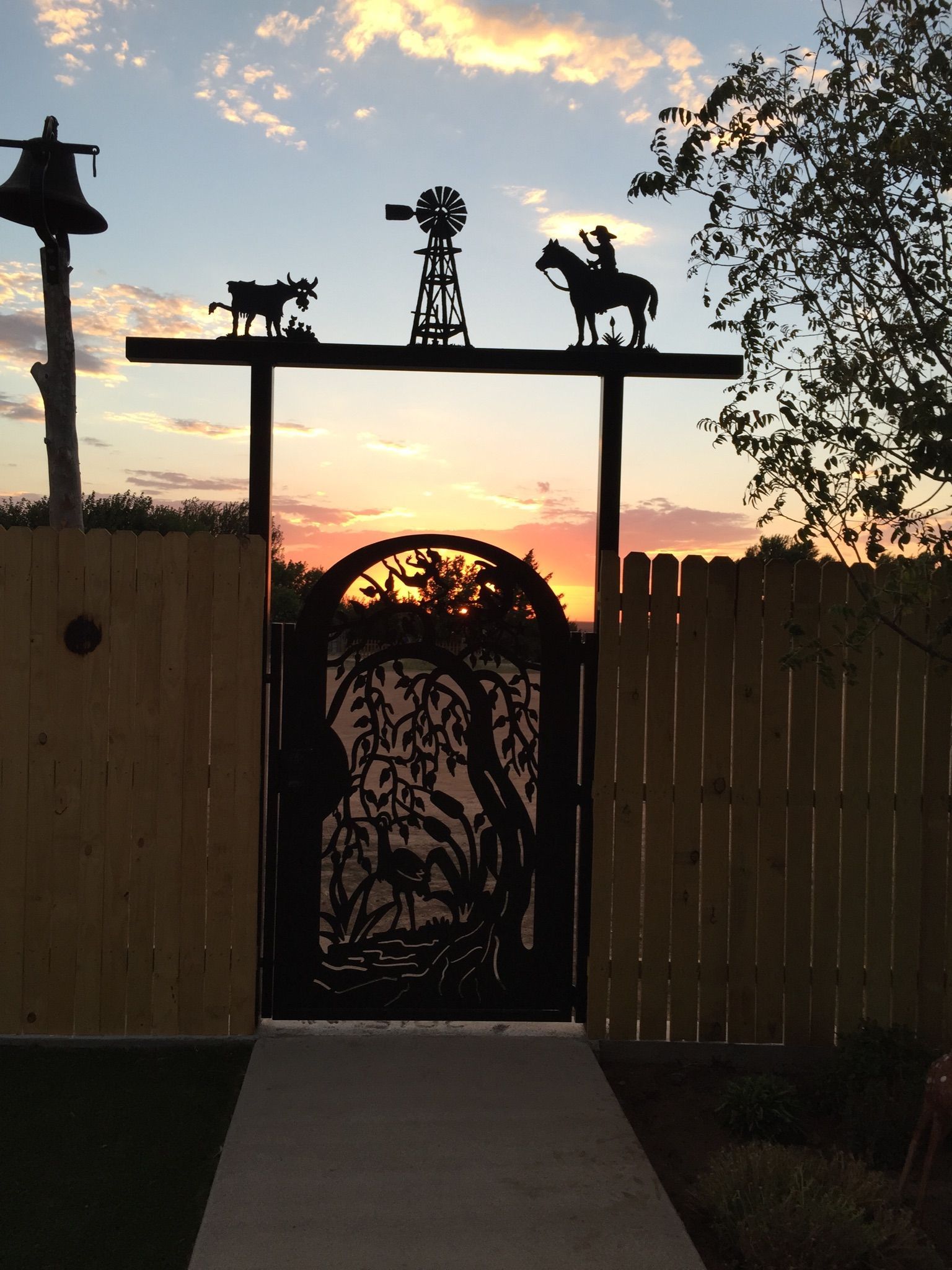 A fence with a gate and a sunset in the background