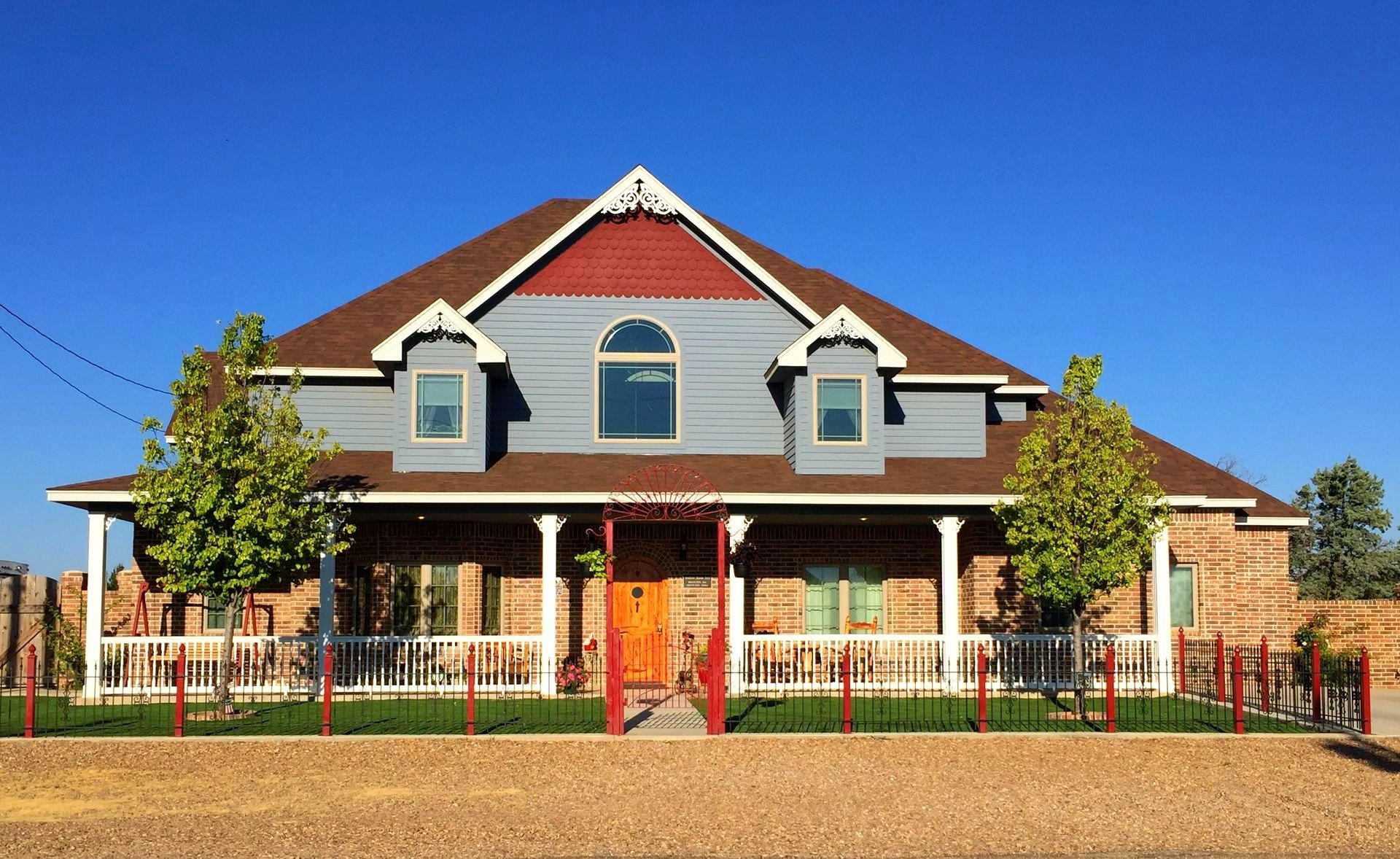 A large house with a large porch and trees in front of it