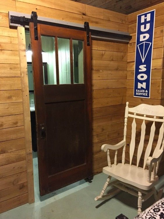 A white rocking chair in front of a sliding barn door that says hudson