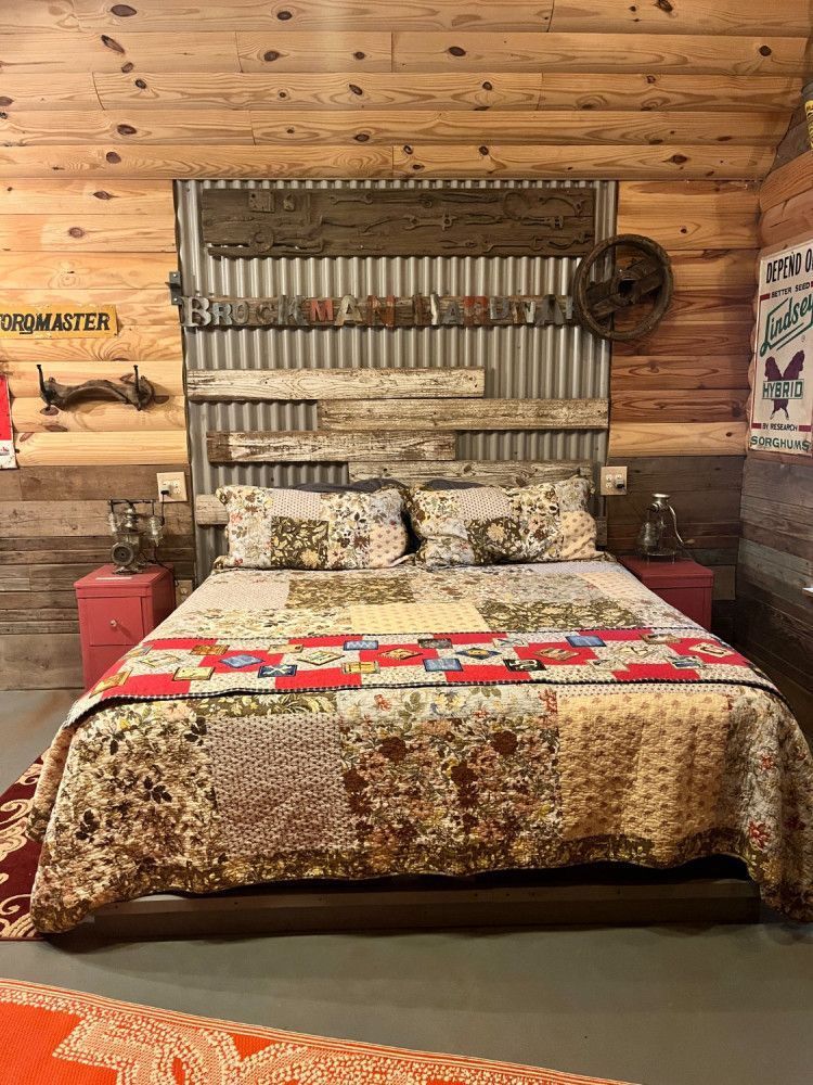 A bed with a quilt on it in a room with a wooden wall.