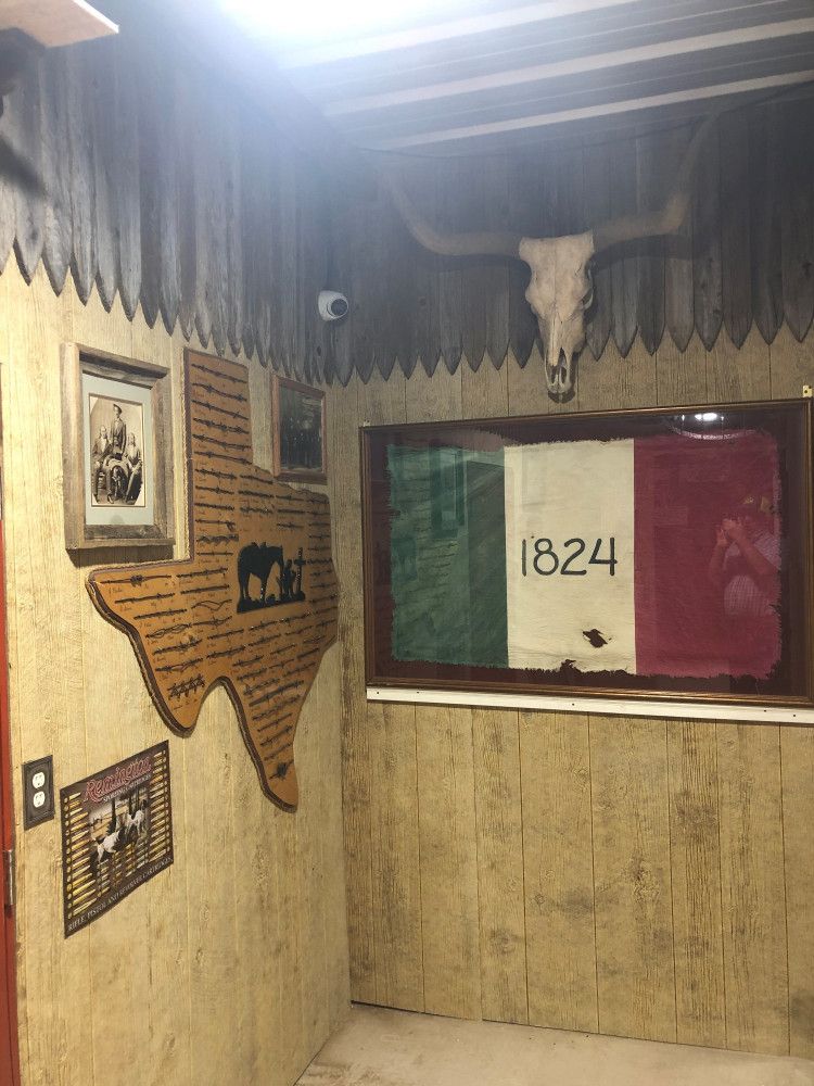 A room with a texas map on the wall and a flag that says 1824