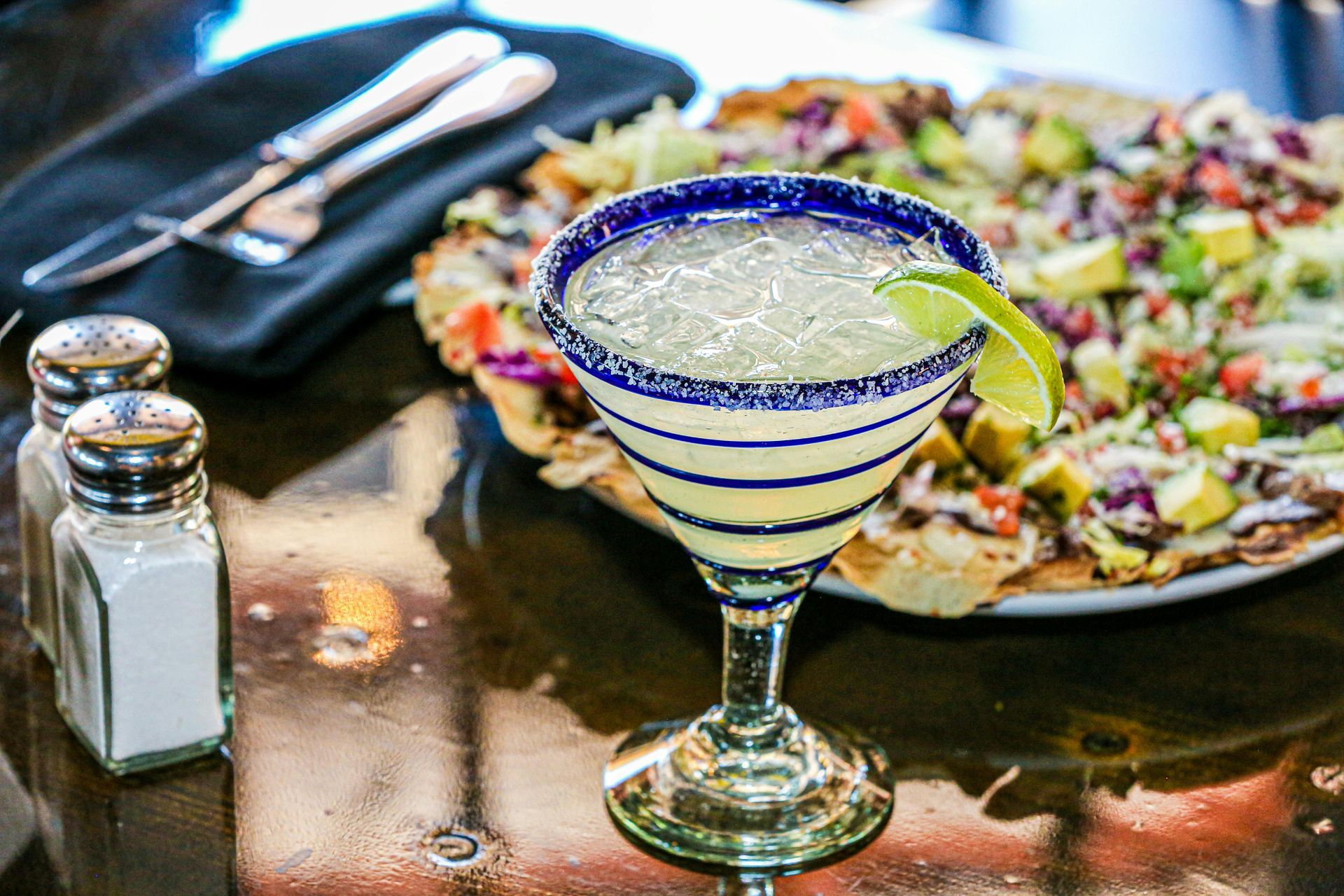 A margarita is sitting on a table next to a pizza.