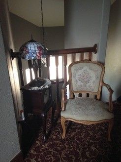 A chair is sitting in a hallway next to a lamp and a clock.