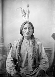 A black and white photo of a native american man with feathers on his head.