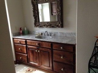 A bathroom with a sink , mirror and wooden cabinets.