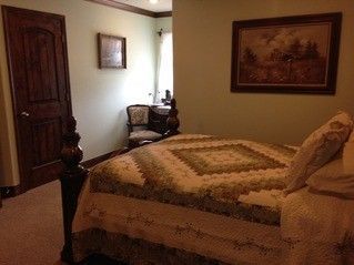 A bedroom with a bed , chair and painting on the wall.