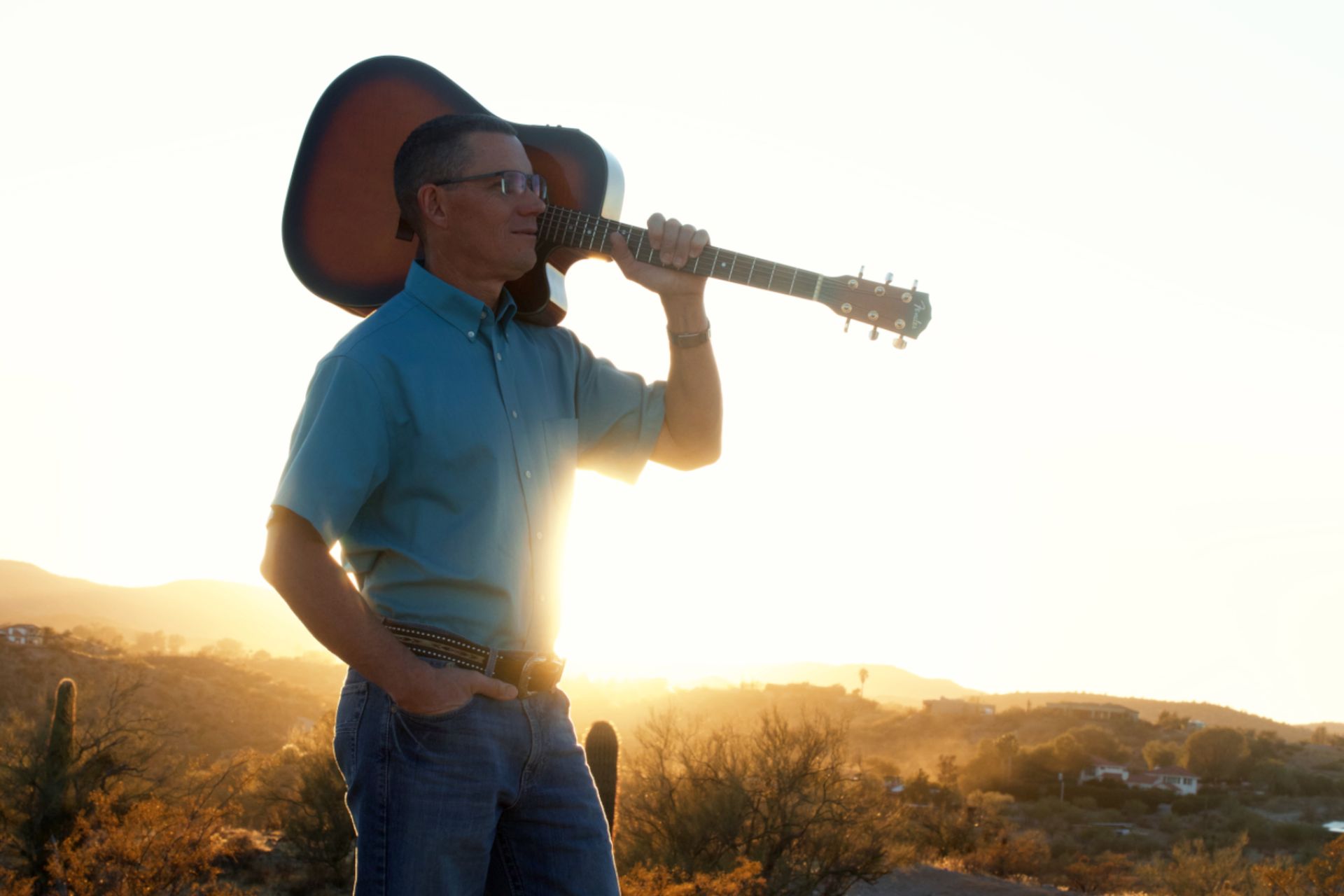 A man is holding a guitar over his shoulder.