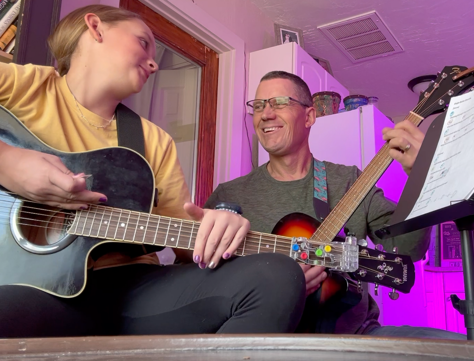 A man and a woman are playing guitars in a room.