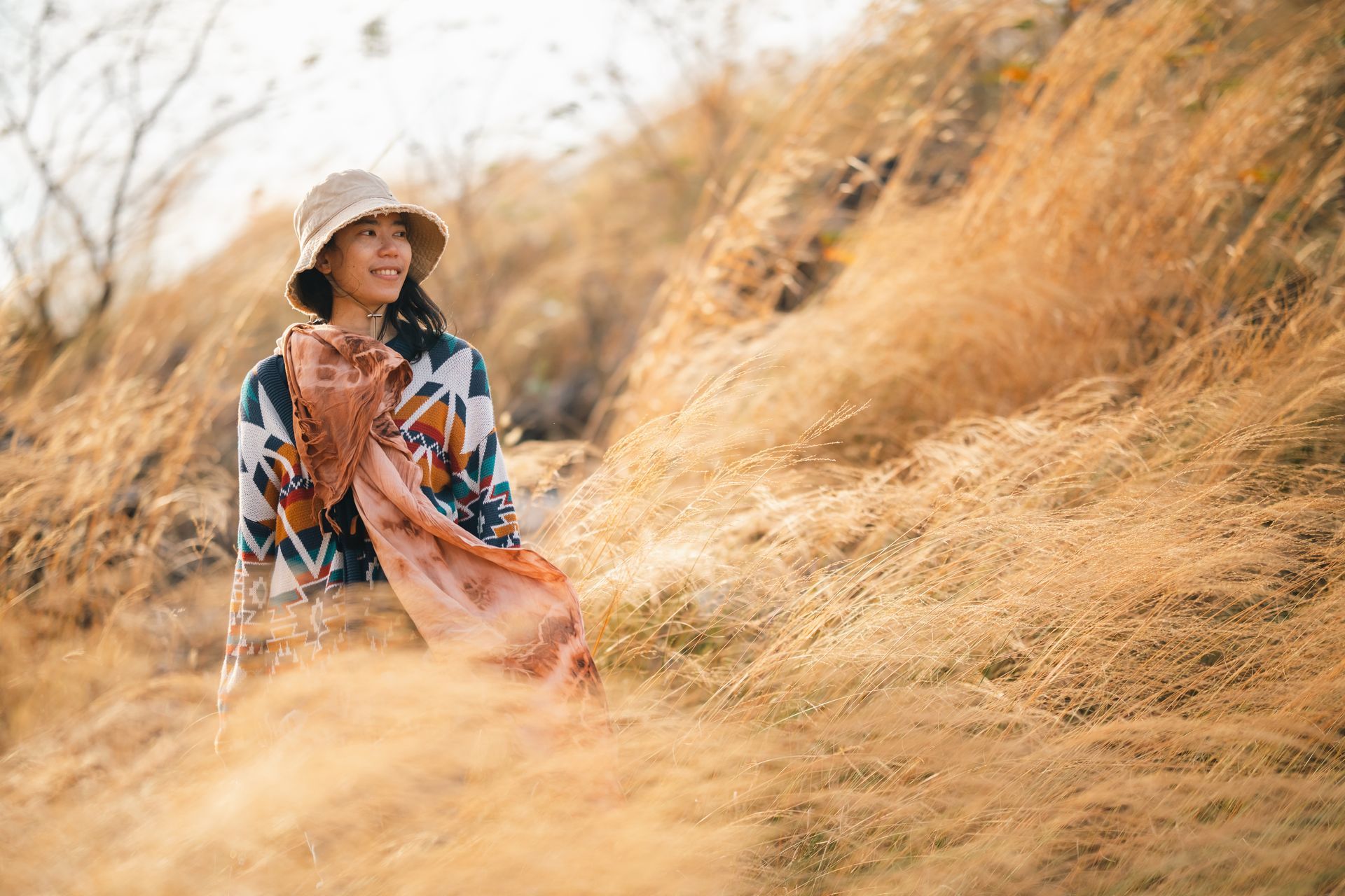 Person writing with a pen in an open notebook, beige tones, blurred background with yellow couch.