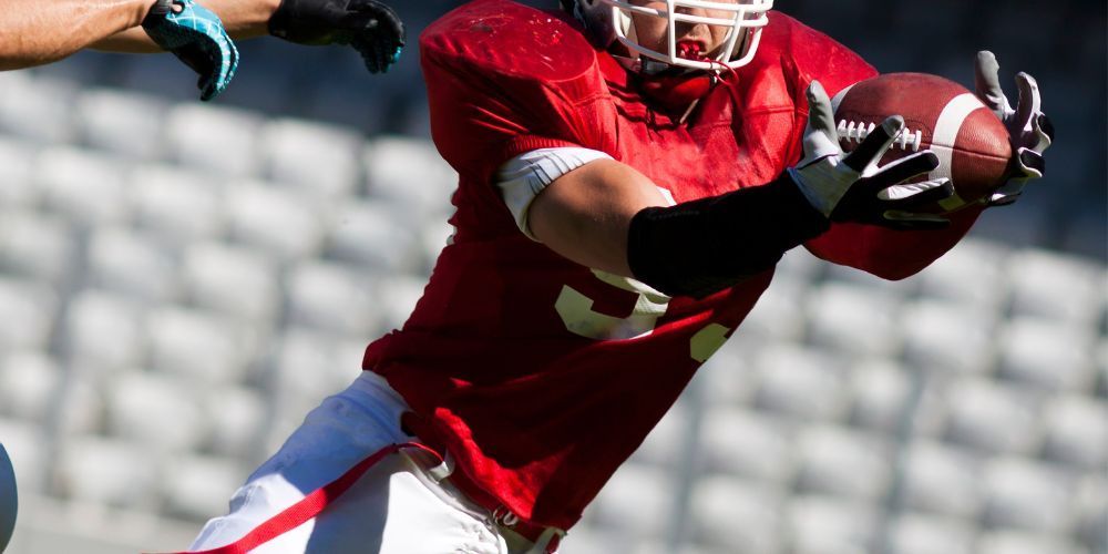 A football player in a red uniform is trying to catch the ball