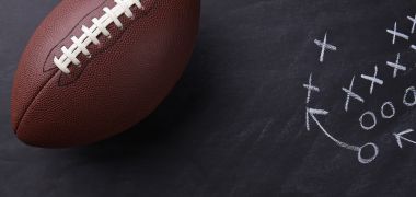 A football is sitting on top of a blackboard with a strategy drawn on it.
