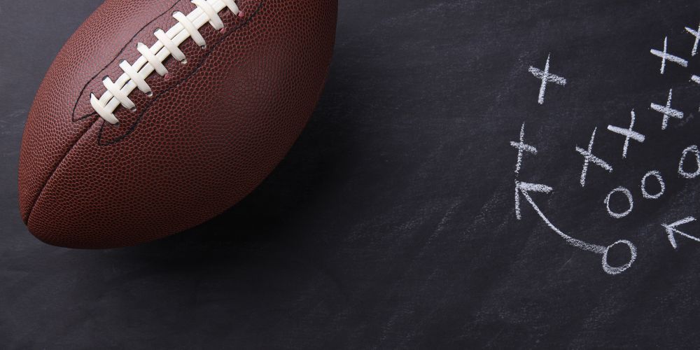 A football is sitting on top of a chalkboard with a strategy drawn on it.