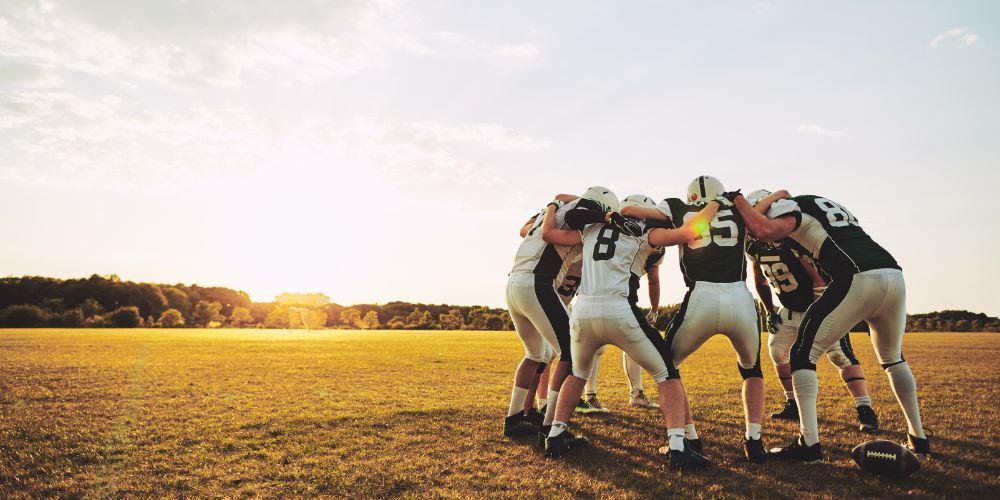 A group of football players are huddled together on a field.