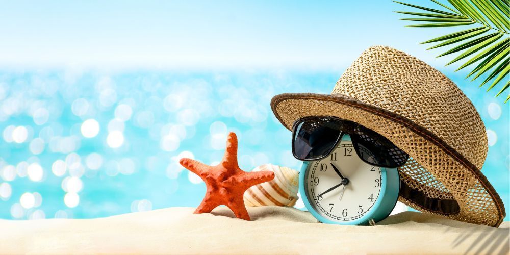 A straw hat , sunglasses , starfish , and a clock on the beach.