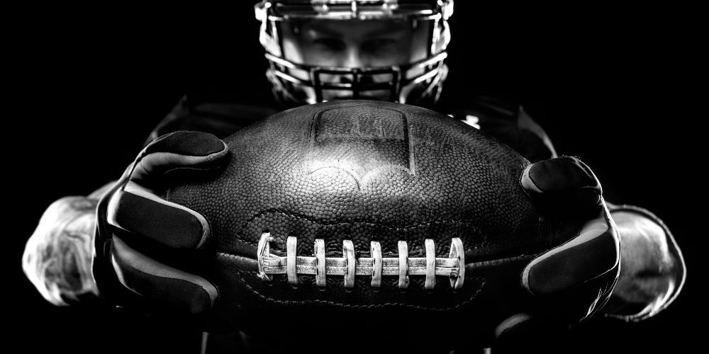 A football player is holding a football in his hands in a black and white photo.