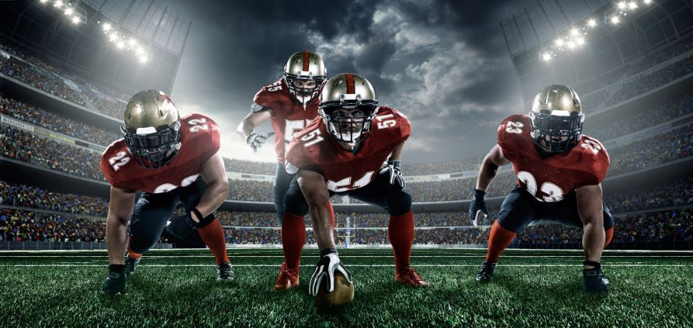 A group of american football players are standing on a field.
