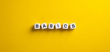The word basics is written on white cubes on a yellow background.